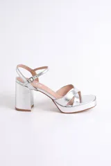 Sandalias plateadas de fiesta con plataforma y taco cuadrado. Presenta cruce de tiras en el frente y pulsera con hebilla regulable al tobillo.