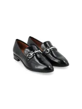 Zapato mocasín de cuero charol negro con detalle de hebilla plateada.