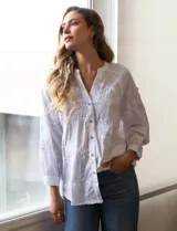 Blusa blanca de algodón bordado, marca Hetser & Orchard. Cuello a la base, escote en V y abertura central con botones. Manga larga amplia.