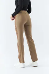 Pantalón de vestir color café con corte recto, tiro alto y elástico en la cintura. Presenta bolsillos laterales y detalle de cuero en los laterales.