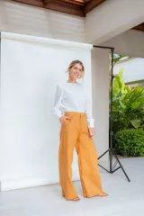 Pantalón de lino color mostaza, de tiro alto, corte clásico a la cintura con pinzas y pierna ancha.