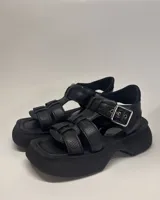 Sandalias negras de cuero vacuno con plataforma y tiras anchas entrecruzadas.