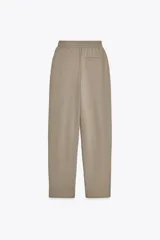 Pantalón color arena de tiro medio con cintura elástica, bolsillos laterales ocultos y pinzas en el delantero.