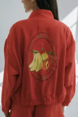 Bomber color coral confeccionada en mezcla de algodón y lino, con cierre frontal y puños elásticos. Presenta un bordado grande en la espalda inspirado en la colección La Verdulería.