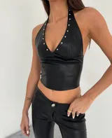Corset negro de cuero sintético con escote halter y tachas plateadas.