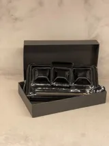 Billetera tipo clutch de cuero charol negro con cierre de cremallera y solapa con tres apliques piramidales.