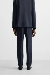 Pantalón de vestir azul marino, de corte recto, con pinzas frontales, bolsillos laterales y traseros de ojal. Se cierra con cremallera y doble botón.