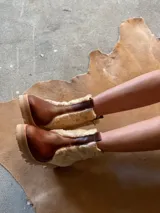 Botas de cuero marrón con paneles de corderito en color beige en la caña. Cuentan con una suela de goma tipo track en tono tostado y cierre de cremallera lateral.