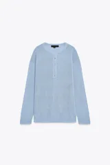 Jersey celeste de punto liso, con cuello redondo, manga larga y botones delanteros.