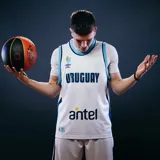 Camiseta de básquet Umbro de Uruguay, modelo alternativo. Diseño blanco con detalles celestes y el logo de Antel en el frente.