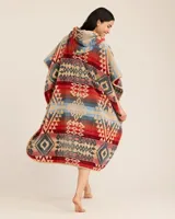 Poncho de toalla con capucha confeccionado en algodón con tejido jacquard. Presenta un diseño geométrico multicolor de inspiración tribal en tonos rojo, azul y beige. Cuenta con un exterior aterciopelado y un interior de bucles absorbentes, ideal para usar después de la piscina o la playa.