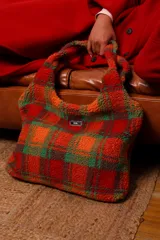 Bolso tipo tote de corderito cuadrillé en tonos rojo, naranja y verde, con forro de algodón cuadrillé blanco y negro y cierre de botón a presión.