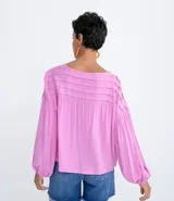 Blusa tipo blusón color rosado, de viscosa, con cuello redondo, manga larga acampanada, pliegues en los hombros, detalle de entredós en el escote y tiras de ajuste con borla.