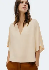 Blusa color crema con escote en V y mangas cortas amplias.
