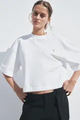 Camiseta blanca de algodón, corte oversize, cuello redondo, manga corta y detalle de aplique metálico con logo ZA en el frente.