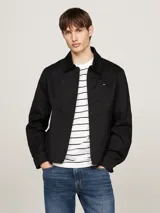 Campera negra Tommy Hilfiger de corte regular, confeccionada en puro algodón, con cuello inglés, cierre de cremallera, dos bolsillos diagonales en la cintura, un bolsillo interior abierto, puños con botón, forro completo y logo de Tommy Hilfiger bordado en el pecho.