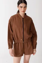 Campera bomber marrón de corte moderno confeccionada en mezcla de algodón y lino, con cierre frontal y bordado grande en la espalda inspirado en la colección La Verdulería.