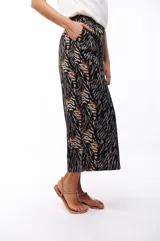 Pantalón capri negro con estampado abstracto en tonos beige, gris y marrón.