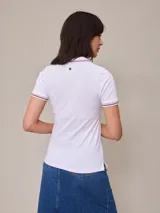 Remera polo blanca de piqué con cuello sin botones y mangas cortas con ribete a rayas rojas y azules. Corte clásico.