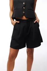 Short negro de poliéster y elastano, con pinzas delanteras, bolsillos laterales y cintura alta.