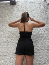 Mono corto negro de lurex con escote halter asimétrico y choker integrado.