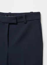 Pantalón crop de tiro bajo, color azul marino, con corte flare, bolsillos laterales y traseros, cierre de cremallera y gancho, trabillas para cinturón y forro interior.