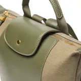 Mochila de mujer confeccionada en material sintético y textil color verde. Presenta una solapa frontal con broche a presión, cierre superior metálico y asa corta de mano. Incluye correas traseras regulables y logo metálico XL en el frente.