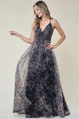 Vestido largo de fiesta con estampado floral en tonos grises, negros y rosados. Tiene escote en V, tirantes finos y falda amplia de organza.