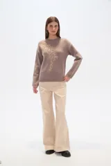 Sweater color lila con apliques de lentejuelas doradas formando un diseño floral en el frente.