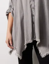 Camisa celeste de tencel, corte amplio, con cuello mao, escote en V y abotonadura frontal. Tiene bolsillos aplicados en el pecho, mangas 3/4 regulables con presilla y ruedo desflecado.