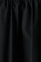 Pollera mini circular negra de algodón con tiras a ambos lados de la cintura y cierre oculto en un lateral.