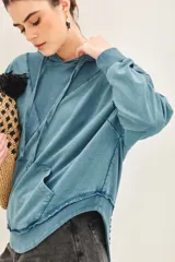 Buzo oversize color celeste de rústico de algodón con capucha forrada y terminaciones al corte.