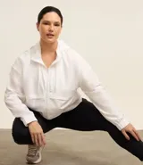 Campera deportiva femenina alargada con capucha y tecnología cortaviento. Incluye cuerda de ajuste en la capucha, cierre delantero por cremallera y saquito para guardar.