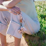 Billetera elástica color marrón con estampado de flores rosas, marca Thread.