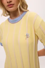 Vestido de tejido de punto, color negro con rayas verticales grises. Tiene cuello redondo y puños y ruedo en color rojo con costuras decorativas en hilo azul. Presenta un pequeño bordado de una letra 'B' estilizada en el pecho.