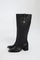 Bota bucanera de cuero color marrón, con caña alta, punta fina y taco cuadrado. Presenta detalle de costuras verticales en la caña y cierre lateral.