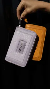 Billetera mediana color beige con textura croco, cierre alrededor y logo Lincoln's.