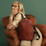 Mochila negra de símil cuero, con cierre principal y bolsillo interno con cierre. Tiene asa de mano, correas regulables y bolsillo oculto en la espalda.