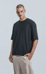 Remera negra de corte crop y calce oversize, con hombros caídos y cuello redondo.
