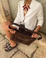 Bandolera de cuero marrón con correa corta y correa larga intercambiables, forro interior y bolsillo con cierre.