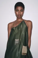 Bolso mini tipo saco confeccionado con hilo metalizado color dorado en forma de malla. Detalle de flecos metálicos labrados. Asa tipo cordón metálica.