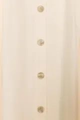 Falda midi color crema de tiro alto, confeccionada en hilatura con lino. Presenta bolsillos laterales ocultos en costura y cierre frontal con botones.