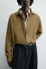 Sobrecamisa color caqui de algodón y lino con efecto arrugado, corte relaxed fit, cuello solapa, manga larga con puños abotonados y cierre frontal con botones.