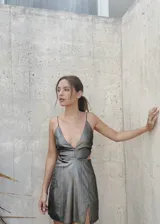Vestido corto plateado metalizado con escote en V profundo, breteles finos, aberturas en la cintura y espalda descubierta.