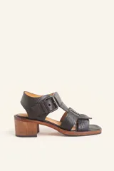 Sandalias negras de cuero texturado con tiras anchas y hebilla lateral. Taco ancho de madera y suela de cuero y goma.