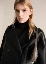 Chaqueta negra efecto piel con cuello de solapa, cierre cruzado con doble botonadura, corte crop y diseño oversize.