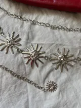 Cadena plateada para la cintura con dijes de soles sonrientes.