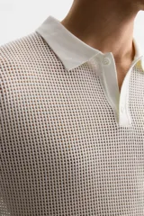 Polo color crudo de punto tejido con estructura calada, corte regular, cuello solapa con abertura frontal y manga corta.