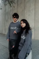 Sweater gris con diseño gráfico en el frente, corte holgado y mangas largas.