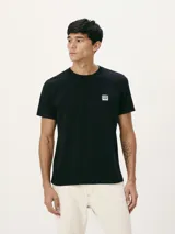 Camiseta blanca de algodón con cuello redondo y mangas cortas. Estampa rectangular con borde negro que contiene la frase "NATURAL ATMOSPHERE" en letras mayúsculas y una imagen de montañas y mar.